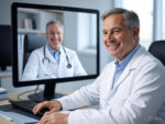 A doctor wearing a white coat engaged in a telemedicine video call, with the patient visible on the computer screen, emphasizing remote healthcare technology.