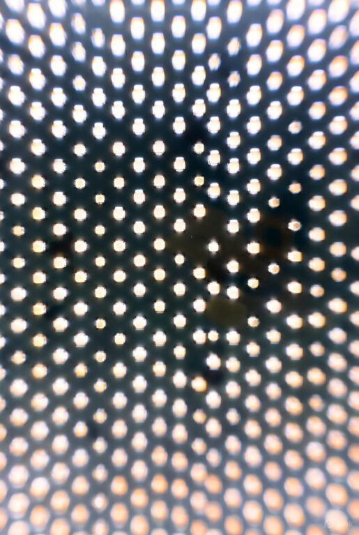 Close-up macro view of a microLED display panel, showing a dense grid of tiny, uniformly lit square pixels on a dark substrate.