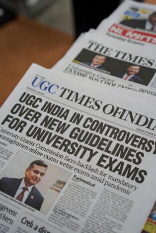 Stack of Indian newspapers with bold headlines about UGC controversy and exams