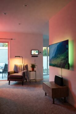 Ambient smart home living space with color-changing lights, wall screen, and voice assistant for dementia-friendly environment