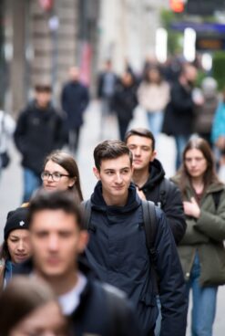 Young man walking alone in a busy urban crowd, unnoticed by surrounding people