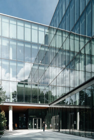 Modern glass office building with people entering under a bright blue sky, representing business opportunities.
